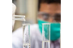 Image A scientist putting liquid into test tubes.